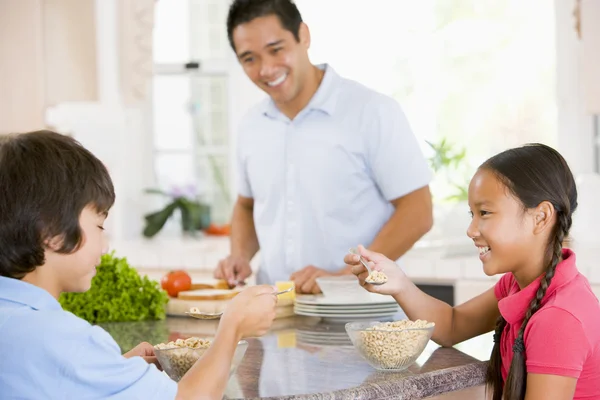 Niños desayunando mientras papá prepara comida —  Fotos de Stock