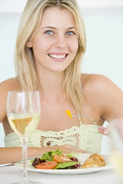 Молодая женщина наслаждается едой, едой со стаканом вина — стоковое фото