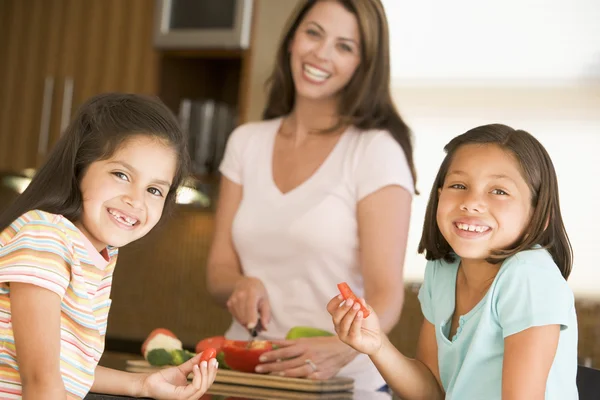 Meisjes peper stroken eten terwijl moeder maaltijd, mealti bereidt — Stockfoto