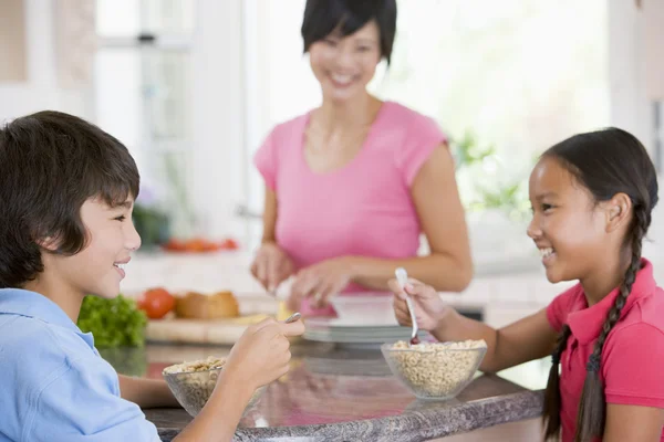 Niños disfrutando el desayuno mientras la madre está preparando la comida —  Fotos de Stock
