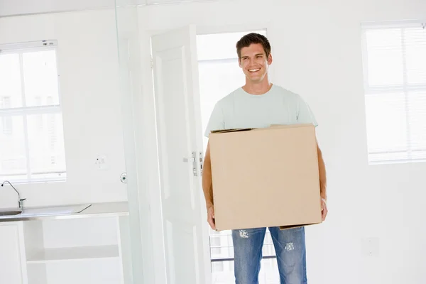 Uomo con scatola trasferirsi in una nuova casa sorridente — Foto Stock