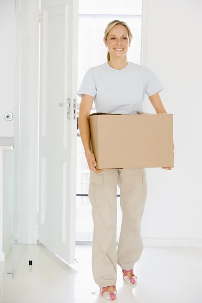 Mujer con caja moviéndose en un nuevo hogar sonriendo —  Fotos de Stock