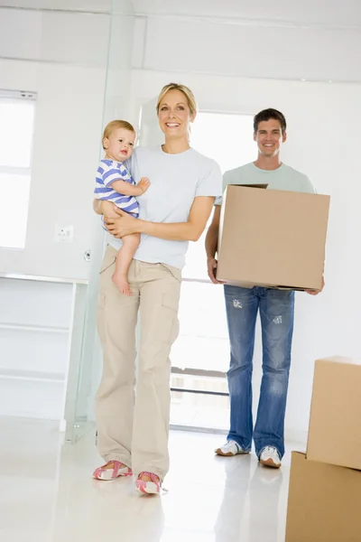Сім'я з коробкою переїжджає в новий будинок посміхаючись — стокове фото