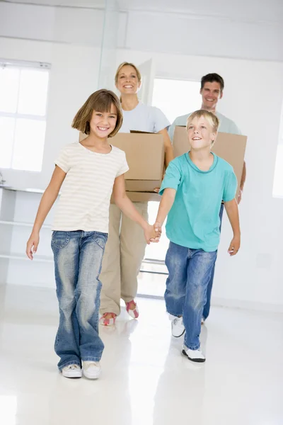 Семья с коробками переезжает в новый дом улыбаясь — стоковое фото