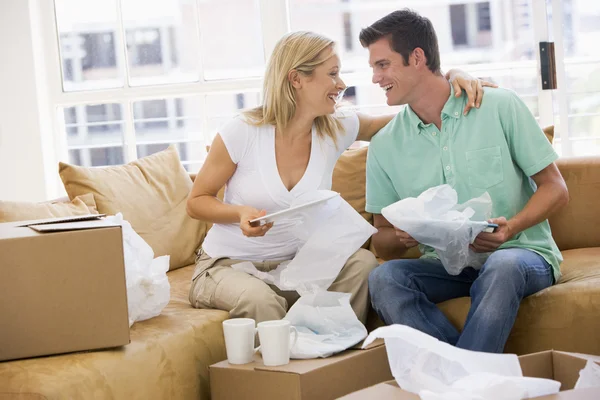 Пара розпаковує коробки в новому будинку посміхаючись — стокове фото
