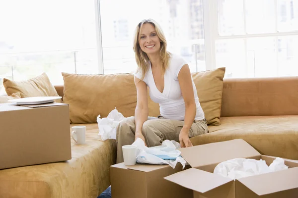 Frau beim Auspacken von Kartons im neuen Zuhause lächelt — Stockfoto