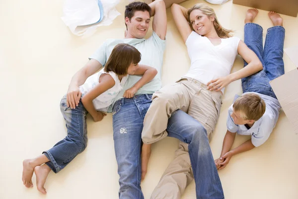 Familie liggend op vloer door open vakken in het nieuwe huis glimlachen — Stockfoto