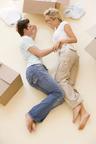 Pareja acostada en el suelo por cajas abiertas en un nuevo hogar sonriendo — Foto de Stock