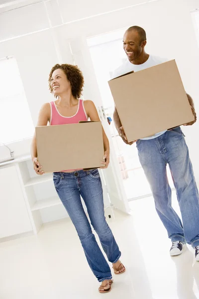 Casal com caixas que se movem para casa nova sorrindo — Fotografia de Stock