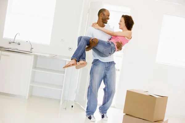 Чоловік тримає дружину в новому будинку посміхаючись — стокове фото