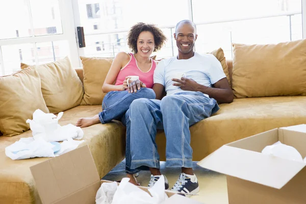 Couple relaxing with coffee by boxes in new home smiling — Stock Photo, Image