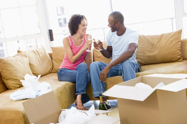 Couple toasting champagne by boxes in new home smiling — Stock Photo, Image