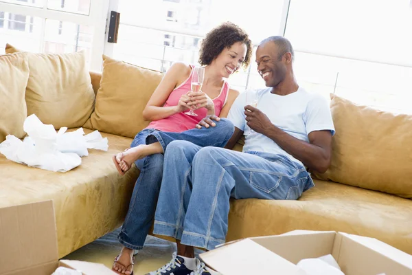 Couple relaxing with champagne by boxes in new home smiling — Stock Photo, Image