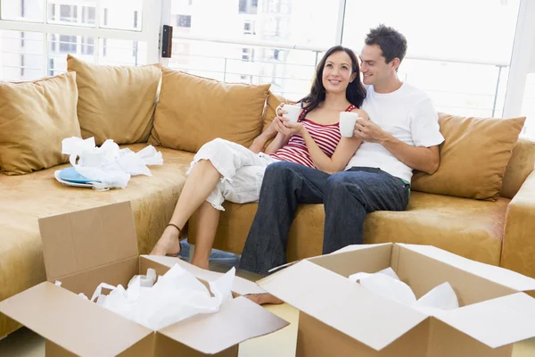 Casal relaxante com café por caixas em nova casa sorrindo — Fotografia de Stock
