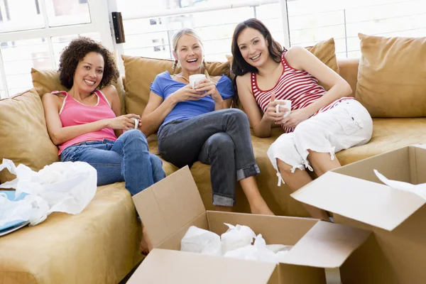 Drei Freundinnen entspannen sich mit Kaffee von Boxen im neuen Zuhause smi — Stockfoto