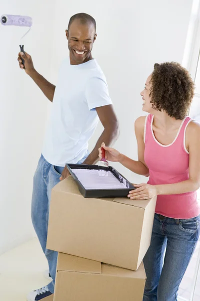Couple with roller and paint in new home smiling — Stock Photo, Image