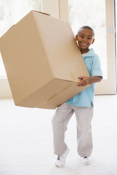 Junge hält Schachtel im neuen Zuhause lächelnd in der Hand — Stockfoto