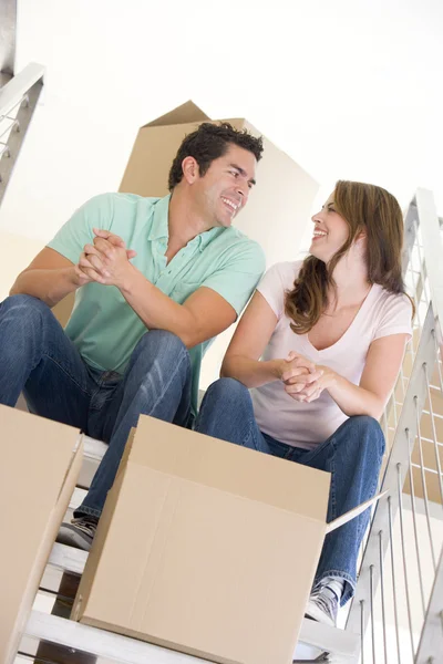 新しいホーム笑顔でボックスと階段の上に座ってカップル — ストック写真