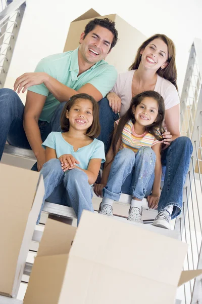 坐在楼梯与中新首页微笑的框上的家庭 — 图库照片
