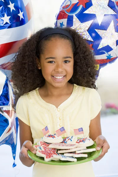 Νεαρό κορίτσι με το τέταρτο του Ιουλίου με μπαλόνια και τα cookies που είναι χαμογελώντας — Φωτογραφία Αρχείου