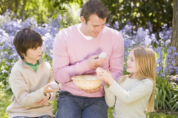 Otce a dvě malé děti na Velikonoce hledá vejce venkovní — Stock fotografie