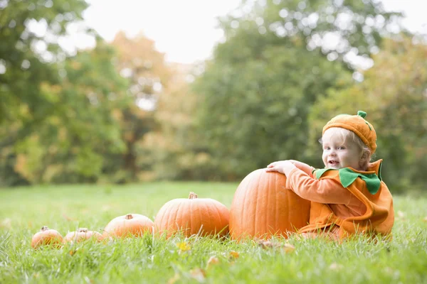 Baby boy outdoors in pumpkin costume with real pumpkins — Stock Photo, Image