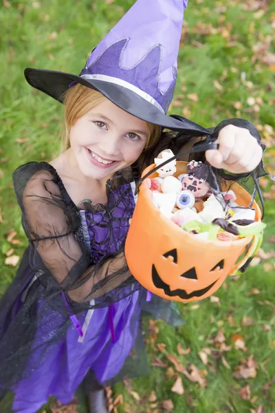Junges Mädchen im Hexenkostüm zu Halloween mit Süßigkeiten — Stockfoto