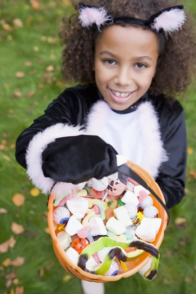 屋外猫衣装ハロウィーンのキャンディーを保持している上で若い女の子 — Stock fotografie