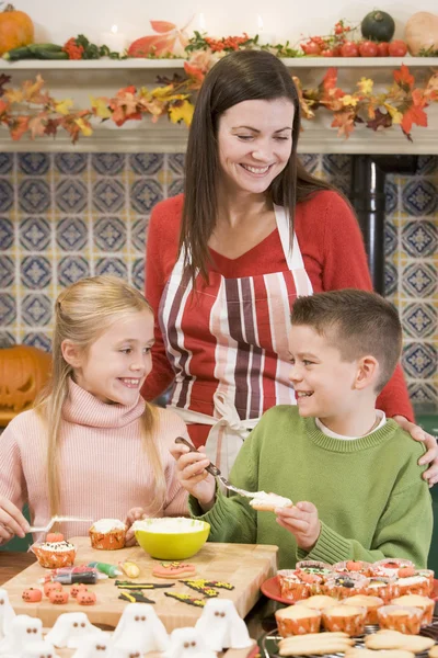 母とハロウィーンのお菓子を作ると笑顔で 2 人の子供 — ストック写真