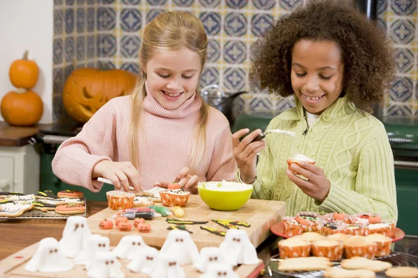 二人の若い女の子友達ハロウィーン菓子を作ることと笑みを浮かべて — ストック写真