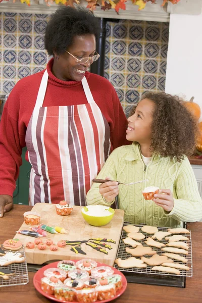 Grandmother and granddaughter making Halloween treats and smilin — Stock Photo, Image