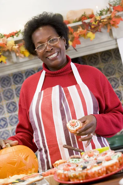 Frau in der Küche macht Halloween-Leckereien und lächelt — Stockfoto