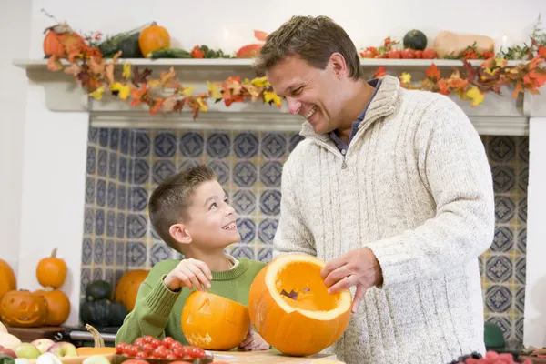 Far och son snida jack o lyktor på halloween och ler — Stockfoto