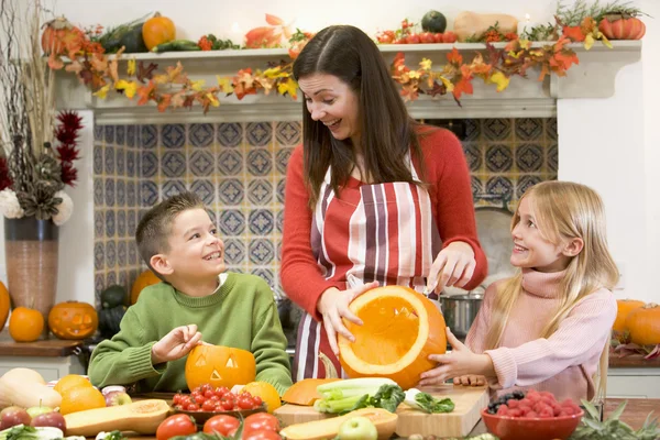Madre y dos niños tallando Jack o linternas en Halloween y —  Fotos de Stock