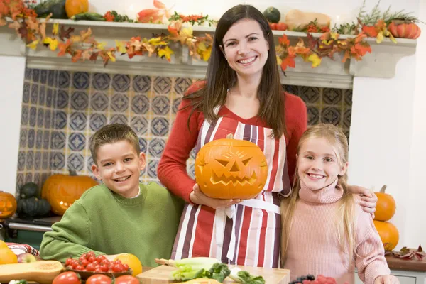 Moeder en twee kinderen snijwerk jack o lantaarns op halloween en — Stockfoto