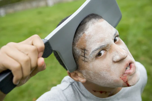 Niño con maquillaje de Halloween aterrador y cuchillo de plástico a través de —  Fotos de Stock