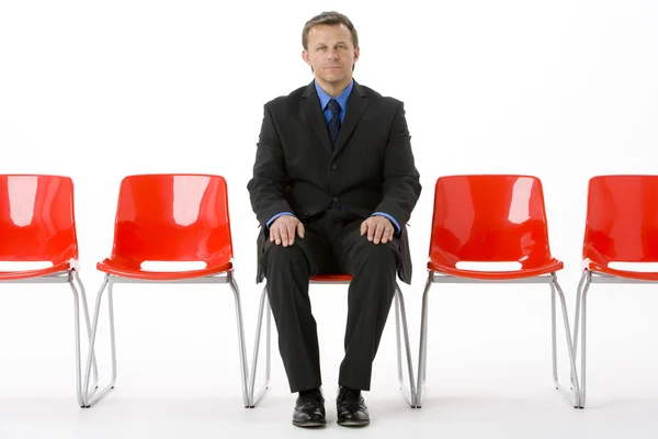 空の椅子の行に座っている実業家 — ストック写真