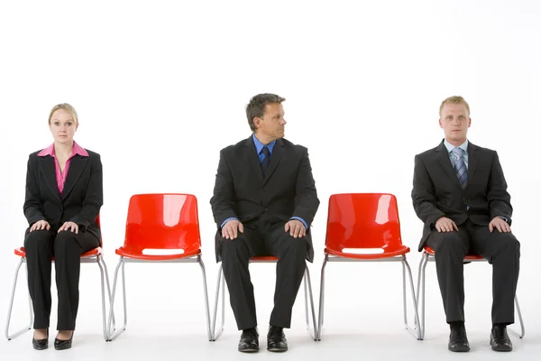 Três negócios sentados em assentos de plástico vermelho — Fotografia de Stock