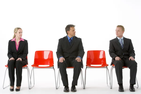 Kırmızı plastik sandalye üzerinde oturan üç iş — Stok fotoğraf