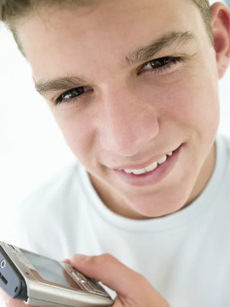 Мальчик-подросток, использующий сотовый телефон и улыбающийся — стоковое фото