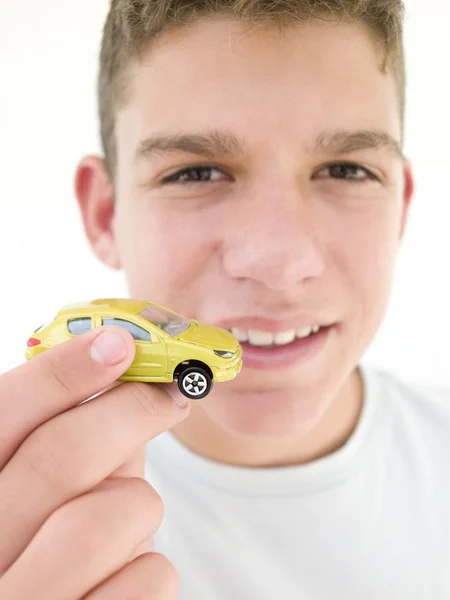 Giovane ragazzo che tiene giocattolo auto e sorridente — Foto Stock