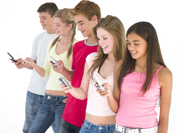Rad med fem vänner använder mobiltelefoner leende — Stockfoto