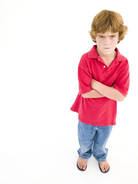 Jeune garçon avec les bras croisés scowling — Photo
