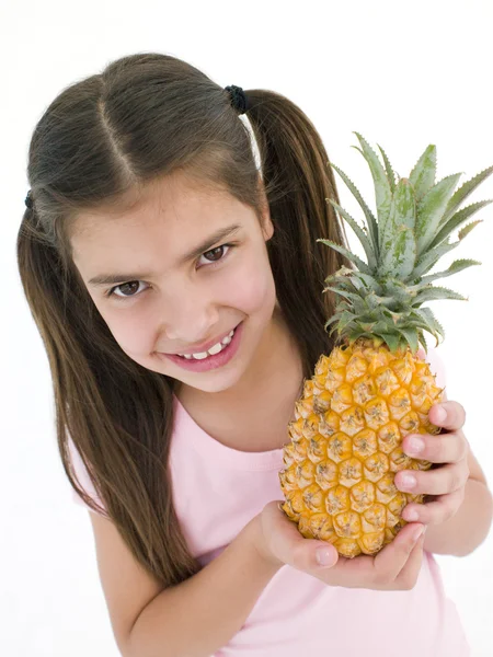 若い女の子パイナップルを保持していると笑みを浮かべて — ストック写真
