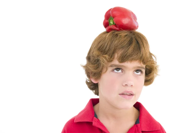 Mladík s červenou paprikou na jeho hlavu, zamračil se — Stock fotografie