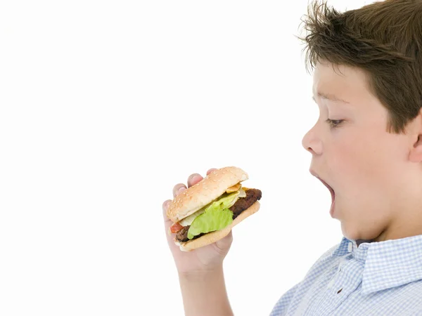 Ung pojke äta ostburgare — Stockfoto