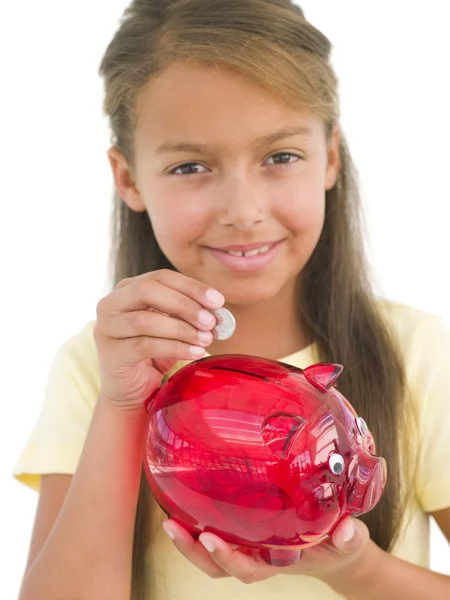Chica joven poniendo moneda en alcancía sonriendo —  Fotos de Stock