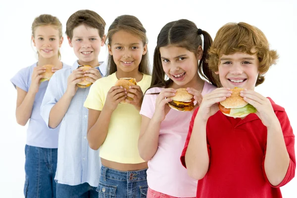 Fila Cinco Jovens Amigos Comendo Hambúrgueres — Fotografia de Stock
