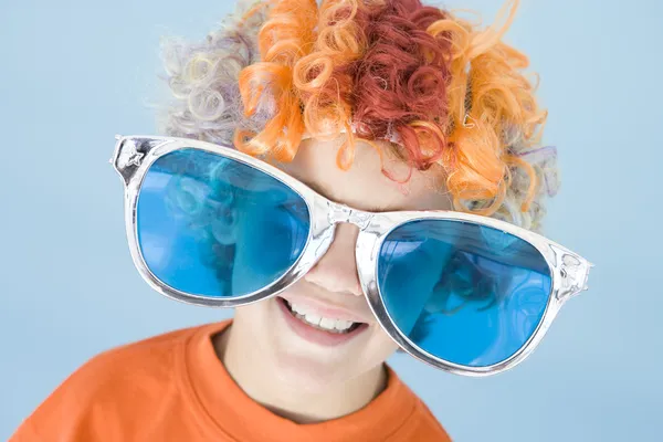 Menino usando peruca de palhaço e óculos de sol sorrindo — Fotografia de Stock