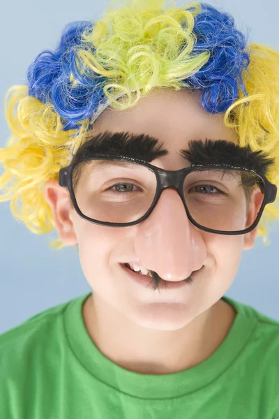 年轻的男孩穿着小丑假发和假鼻子微笑 — 图库照片